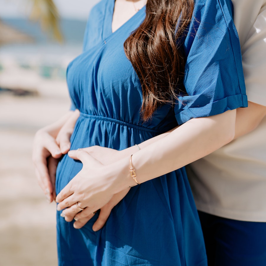 Pregnant woman in blue dress holding her belly